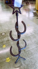HORSE SHOES welded into a stand with star on top.  Not sure - umbrella stand?  cane holder?  fishing poles?  
$35.00